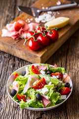 Salad. Fresh summer lettuce salad.Healthy mediterranean salad olives tomatoes parmesan cheese and prosciutto.