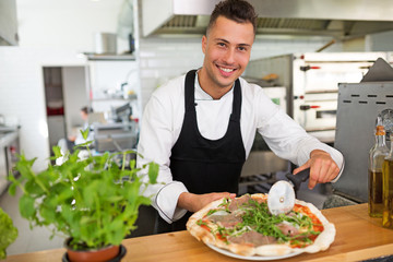Smiling chef preparing pizza in kitchen
