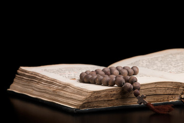Open sacred book for prayer and wooden rosary