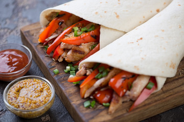 Closeup of tortilla bread stuffed with bbq chicken meat and vegetables, selective focus, shallow depth of field