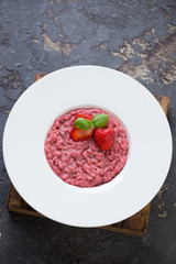 Risotto with strawberries served in a white plate, high angle view over brown stone surface, vertical shot © Nickola_Che