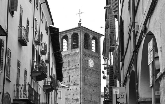 Fototapeta A ancient belfry between old buildings in Pinerolo, Italy. Black and white.