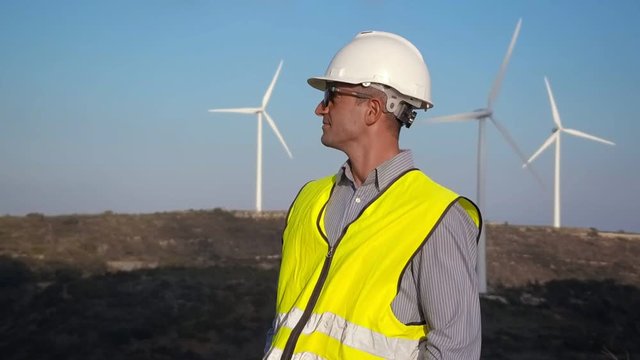 Employee of wind power on the background of windmills