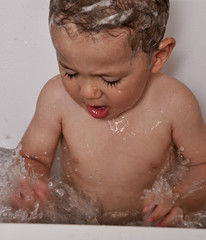 Retrato de un niño en la bañera con shampu, jabón en la cabeza