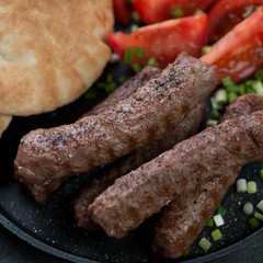 Closeup of grilled cevapi or cevapcici, traditional dish in the Balkans, selective focus