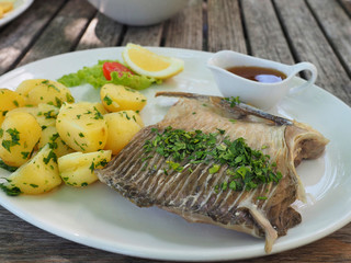 Boiled carp (carp on blue) with boiled potatoes and salad on wooden table.