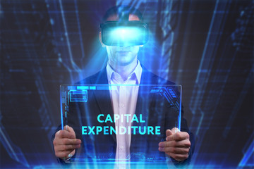 Business, Technology, Internet and network concept. Young businessman working in virtual reality glasses sees the inscription: Capital expenditure