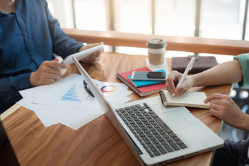 Young worker writing on notebbok while working with colleague
