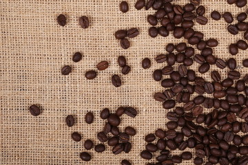 pile coffee beans on jute, linen background and texture, top view
