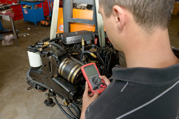 mechanic man with digital multimeter testing ignition coil