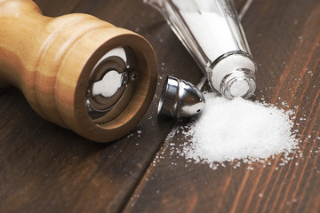 Close-up shot of pair of wooden salts and pepper next to a napkin on wooden table.