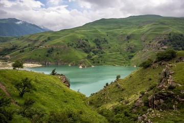 Горный пейзаж, красивый вид на живописное озеро в горном ущелье, облачная погода, зеленые склоны, дикая природа и горы Северного Кавказа