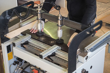 Worker works on the drilling-filler machine that makes furniture.  St. Petersburg. The summer of 2017.
