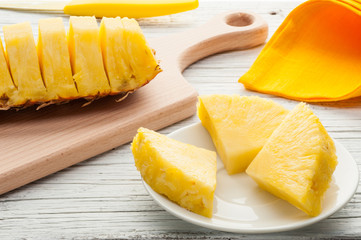 slices of a pineapple on white wooden background