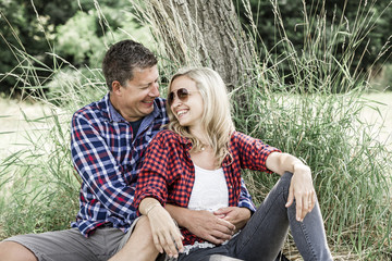 Fototapeta premium young laughing woman with his happy boyfriend sitting on the meadow