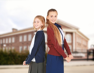 Two cute girls in school uniform on white background