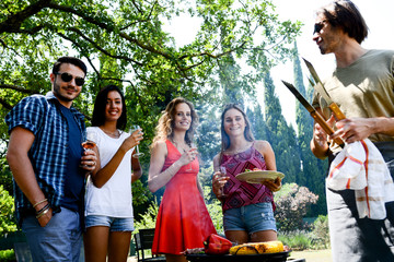 groupe of happy and cheerful young people having fun around barbecue grill during a summer holiday party outdoor in the garden