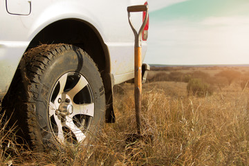 Shovel stuck in a dry field next to a pickup truck © simonmayer