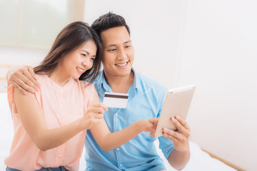 Fototapeta premium Happy Asian couple using tablet and credit card for online shopping