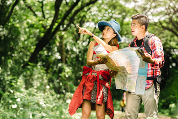 Asian couple in forest checking a map for directions - Powered by Adobe