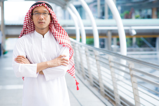 Confident arabian man with arms crossed with city in background