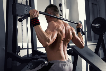 Fototapeta na wymiar Bodybuilder workout on trainer in gym, perfect muscular male body