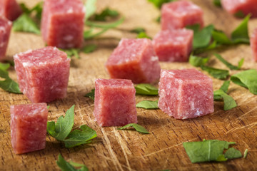 Close-up of small cubes of smoked italian salami on wood