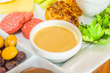 Closeup of traditional Turkish breakfast served in porcelain plate with olive, pastry, parsley, sausage, butter and sesame paste