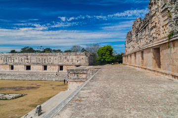 UXMAL, MEXICO - FEB 28, 2016: Tourists at the courtyard of the Nun's Quadrangle (Cuadrangulo de las Monjas) building complex at the ruins of the ancient Mayan city Uxmal, Mexico