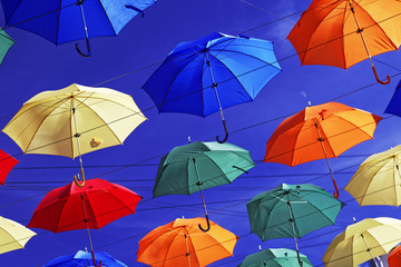 Multi-colored umbrellas in sky above the street. Alley floating umbrellas.