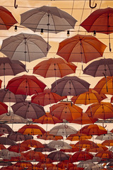 Multi-colored umbrellas in sky above the street. Alley floating umbrellas.