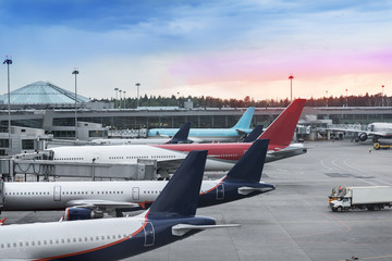 Tails of some airplanes at airport during boarding operations. They are four planes on a sunny evening, with a blue red sky. Travel and transportation concepts. - 162675004