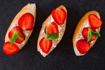On a fashionable dark stone surface set sandwiches with cheese and strawberries, decorated with mint, tasty, healthy, breakfast, beautiful serve, berries, summer