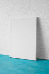 Mock up poster in the interior.  Vertical blank canvas. White wall and blue floor on background.