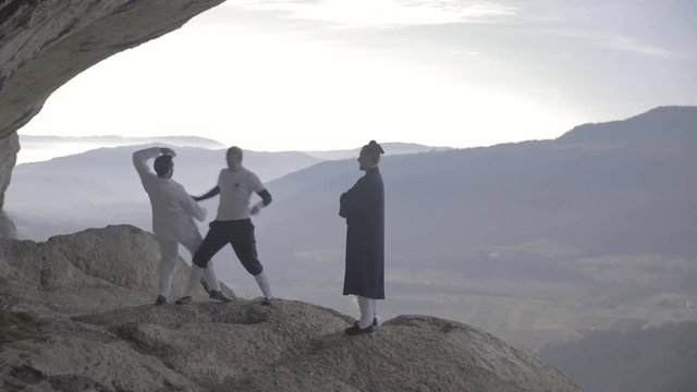 Two trainees practice Kung Fu techniques on a Cliff 4K
