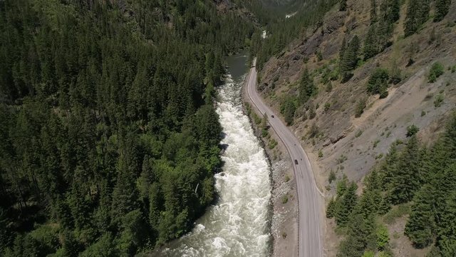 Helicopter Flying Over Cars on Mountain Highway by River in Scenic Sunny Wilderness Beauty