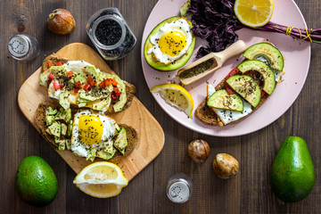 Sandwiches for breakfast with avocado, fried eggs and lemon juice on wooden table top view
