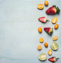 Superfoods and health or detox diet food concept , sliced strawberries, lime and kumquat, space for text on wooden rustic background top view border