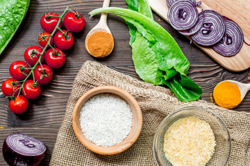 paella home cooking with rice, tomato, onion and spices for ingredients on wooden background top view space for text