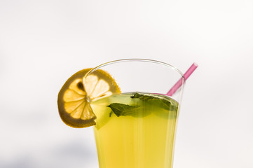 Glass of homemade cold lemonade with fresh lemon slice and mint