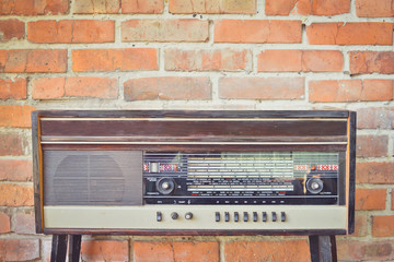 Old vintage antique radio on red brick wall background. Toned image. Copy space.