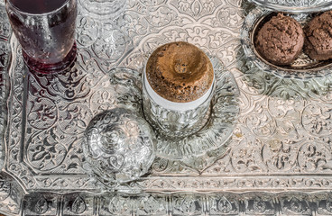 Turkish coffee served with sherbet and cookies in traditional copper serving set