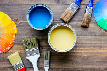 Colorful paints and brushes on grey wooden desk background top view