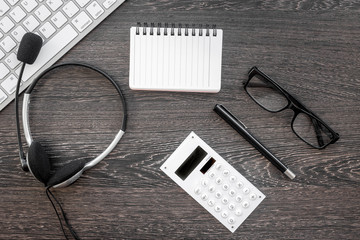 operator headset, notebook and keyboard for contact us feed back call center workdesk stone background top view mockup