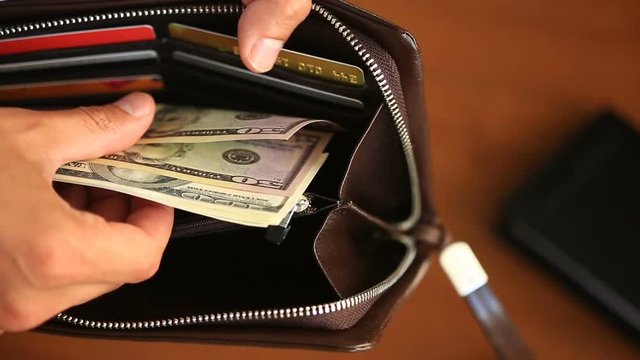 Men's hands hold a purse with dollars