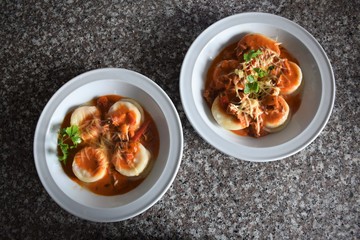 Upper view of two plates of sorrentinos - stuffed pasta - with sauce, parmesan cheese, and decorated with some parsley´s leaves