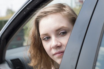 Eine junge Frau blickt aus dem Autofenster nach hinten um den Verkehr zu prüfen