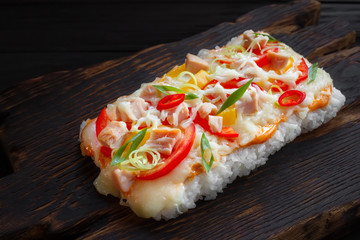 Tasty appetizing japanese rice pizza with bacon served on rustic wooden table.Delicious japanese food