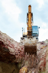 Excavator pours soil from the bucket into the pit
