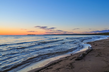 Waves on the shore of Ladoga lake at dawn. Beautiful sunrise landscape.